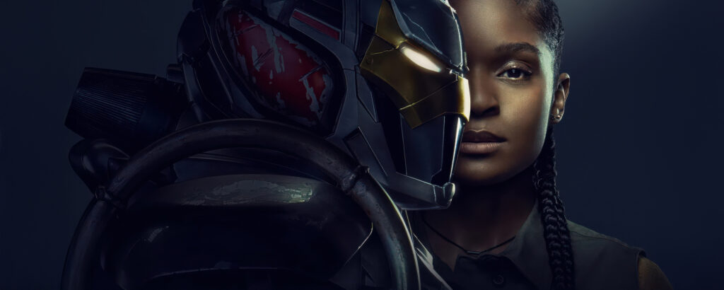 A atriz Dominique Thorne como Riri Williams ao lado de sua armadura da série Coração de Ferro, com o capacete em destaque.